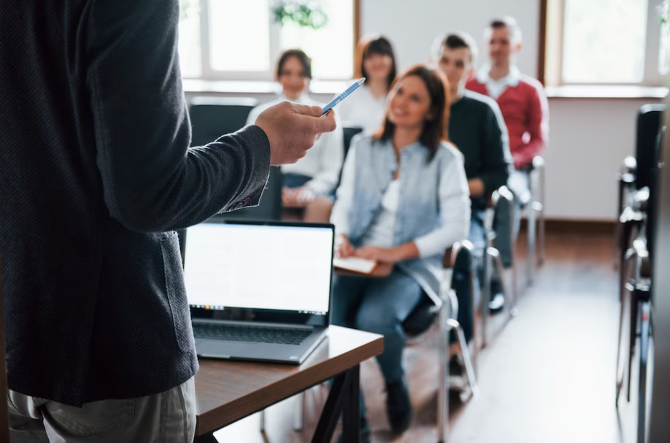 teacher holds a pen, the audience listening in the auditory